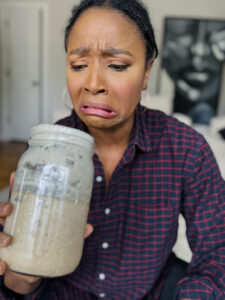 Cierra looking disgusted at her sourdough starter that looks spoiled, but it is not.