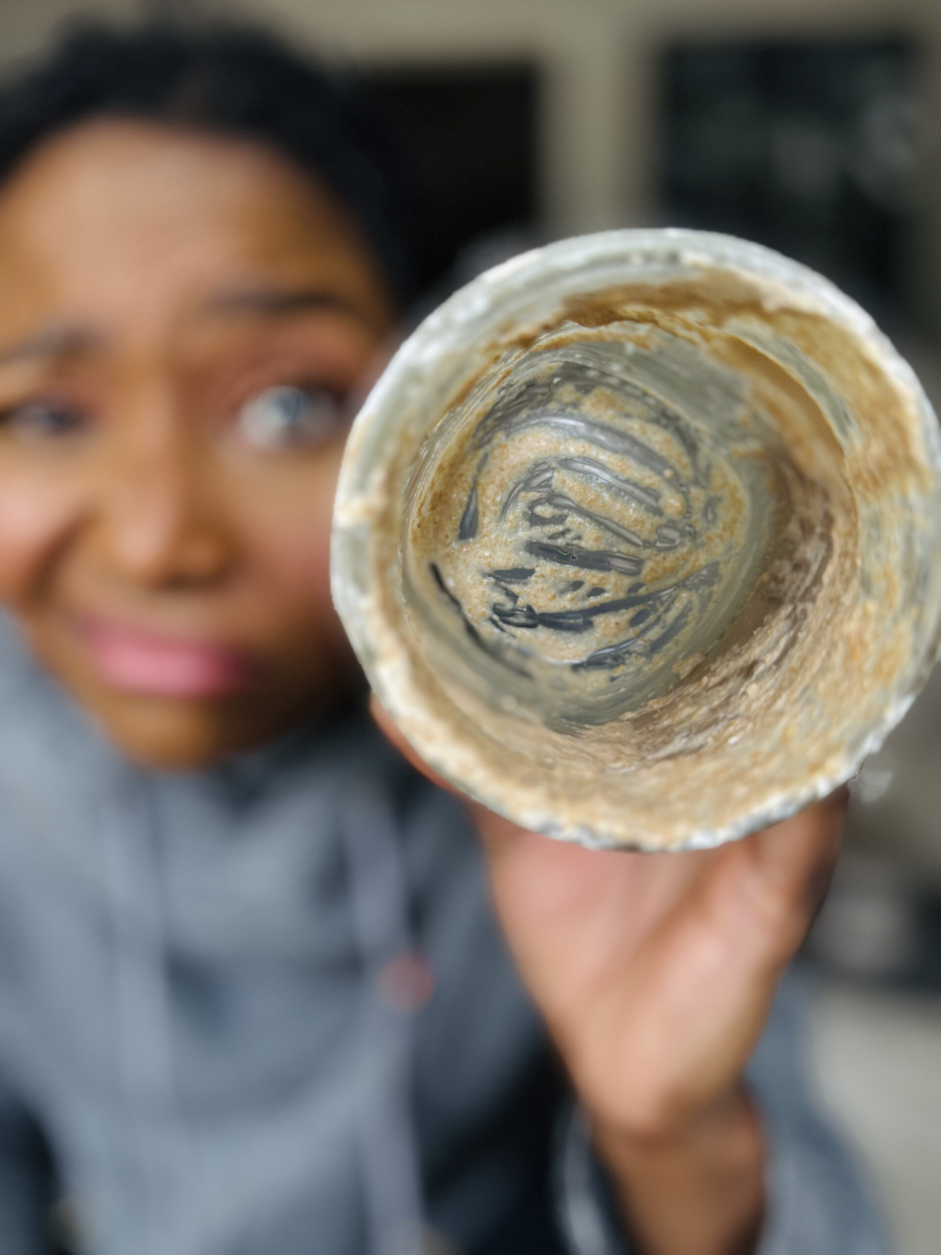 Cierra holding an empty mason jar. The jar has sourdough starter residue around the sides of the jar. This is a close up shot at the inside of the jar.